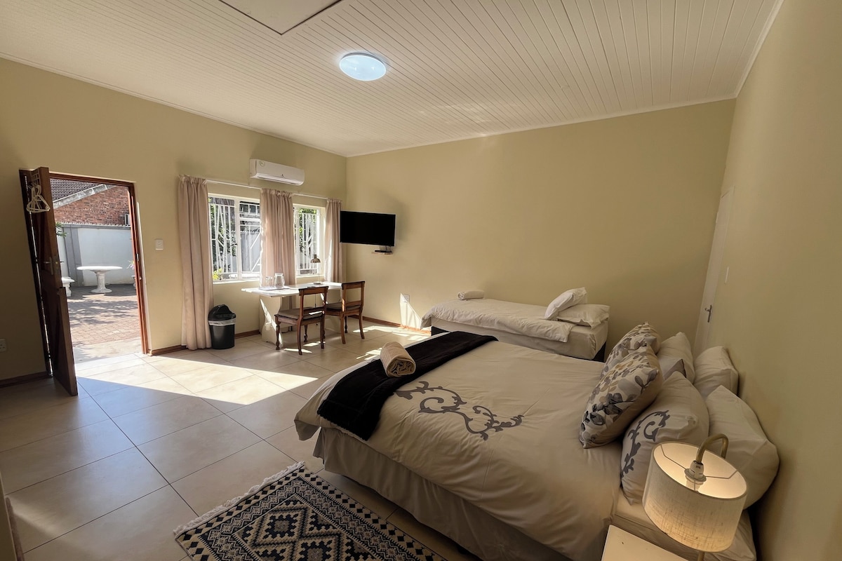 Ein Schlafzimmer mit einem Bett, einem Nachttisch, einer Lampe und einem Schreibtisch mit Stuhl.