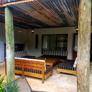 A covered outdoor seating area with wooden furniture and a corrugated metal roof. - Assegaaibosch Country Lodge (Kareedouw)