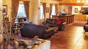 Een ruime woonkamer met een open haard, leren banken en een eethoek.