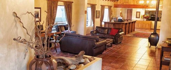 A spacious living room with a fireplace, leather sofas, and a dining area. - Assegaaibosch Country Lodge (Kareedouw)