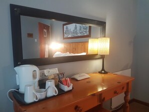 A hotel room with a wooden desk, a coffee maker, mugs, a tissue box, and a lamp. - Assegaaibosch Country Lodge (Kareedouw)