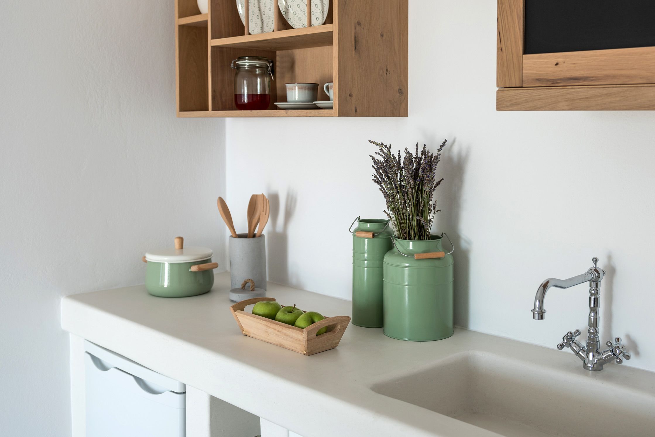 Une cuisine avec un plan de travail blanc, un évier et une étagère en bois au-dessus.