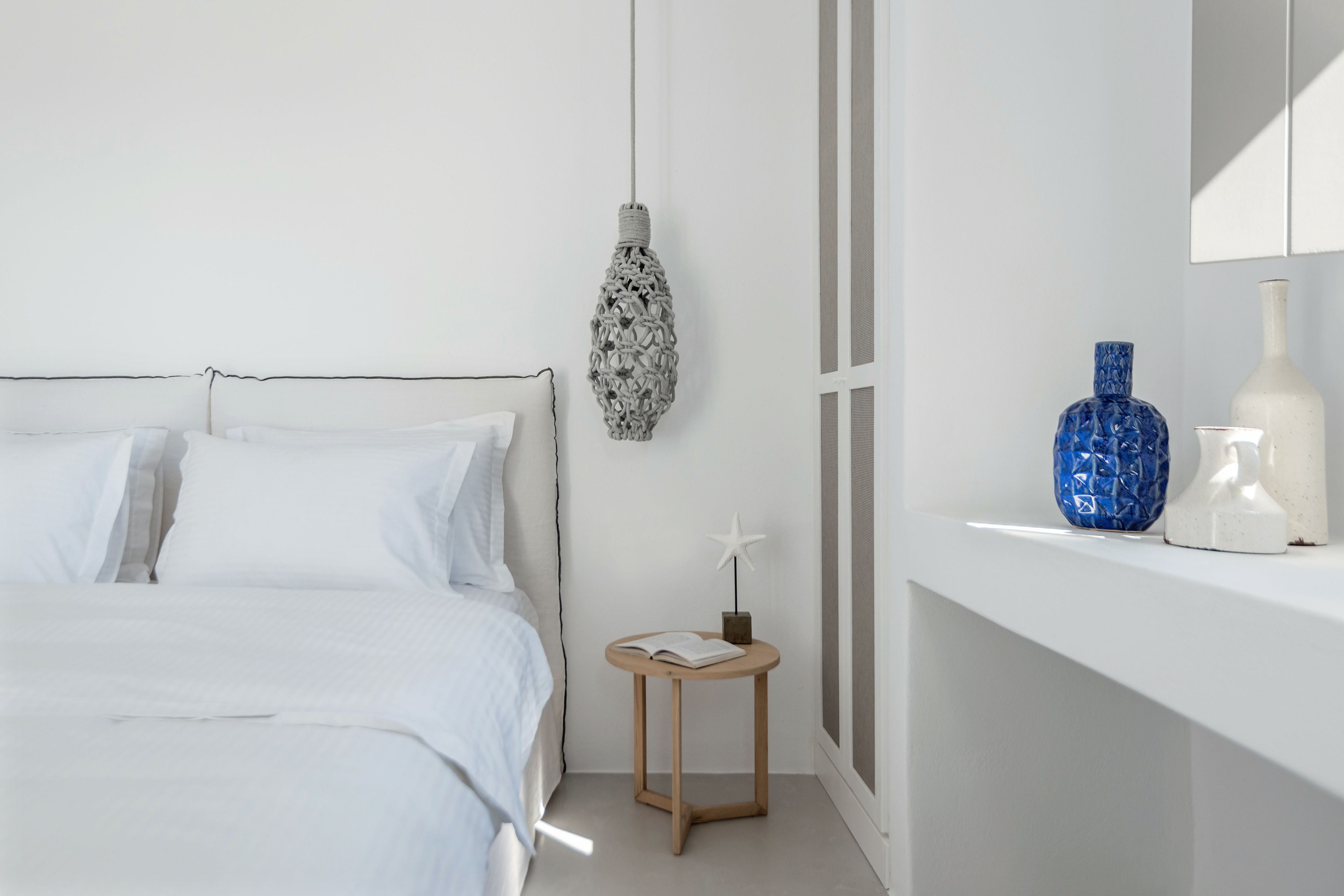Un dormitorio minimalista con cama, mesita de noche y elementos decorativos.