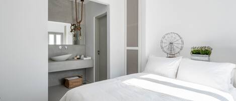 A modern bedroom with a large bed, a built-in vanity with a mirror, and a decorative wall piece.