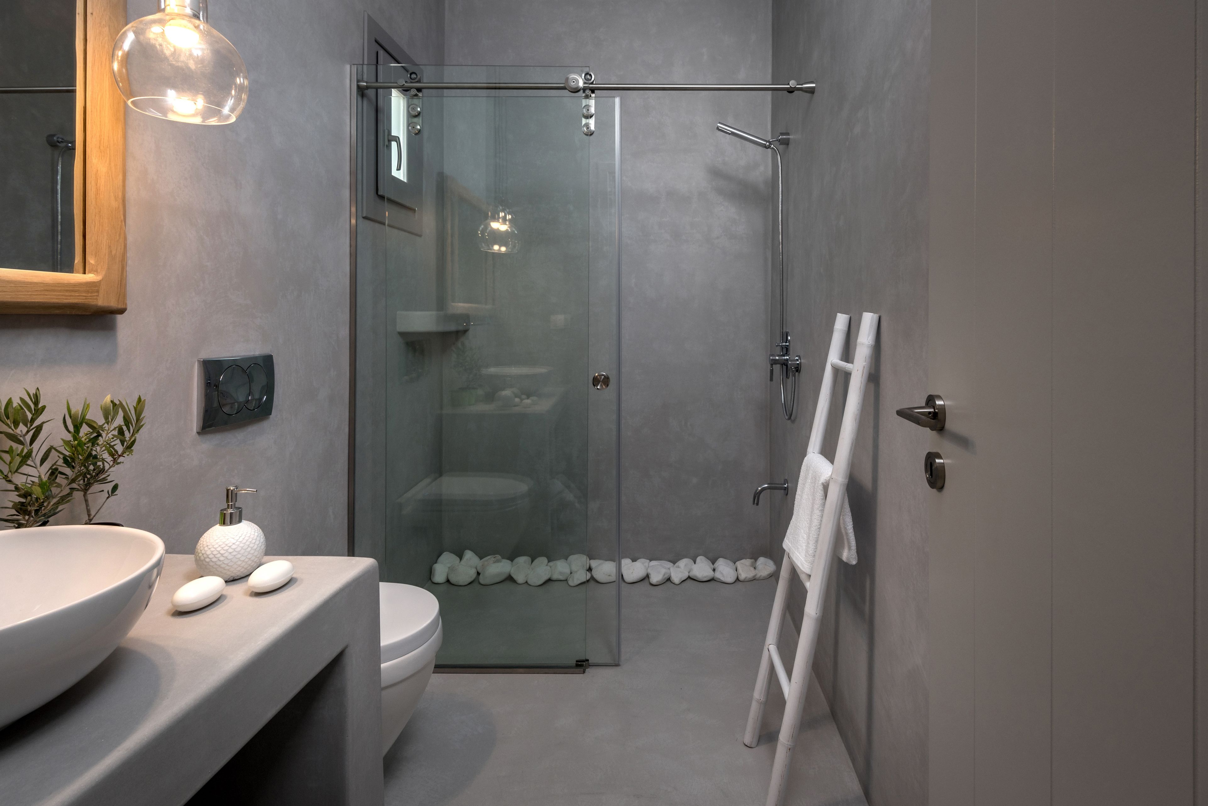 A modern bathroom with a large white sink, a glass shower enclosure, and a white towel rack.