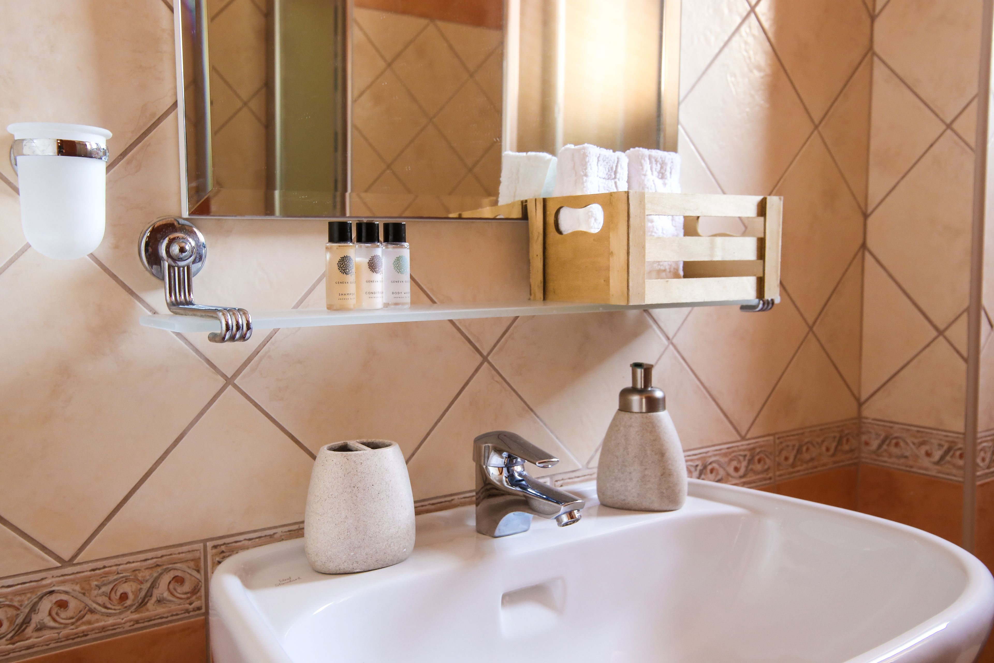 A bathroom with a white sink, a mirror, and a shelf with toiletries.