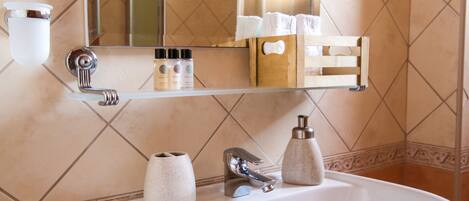 A bathroom with a white sink, a mirror, and a shelf with toiletries.