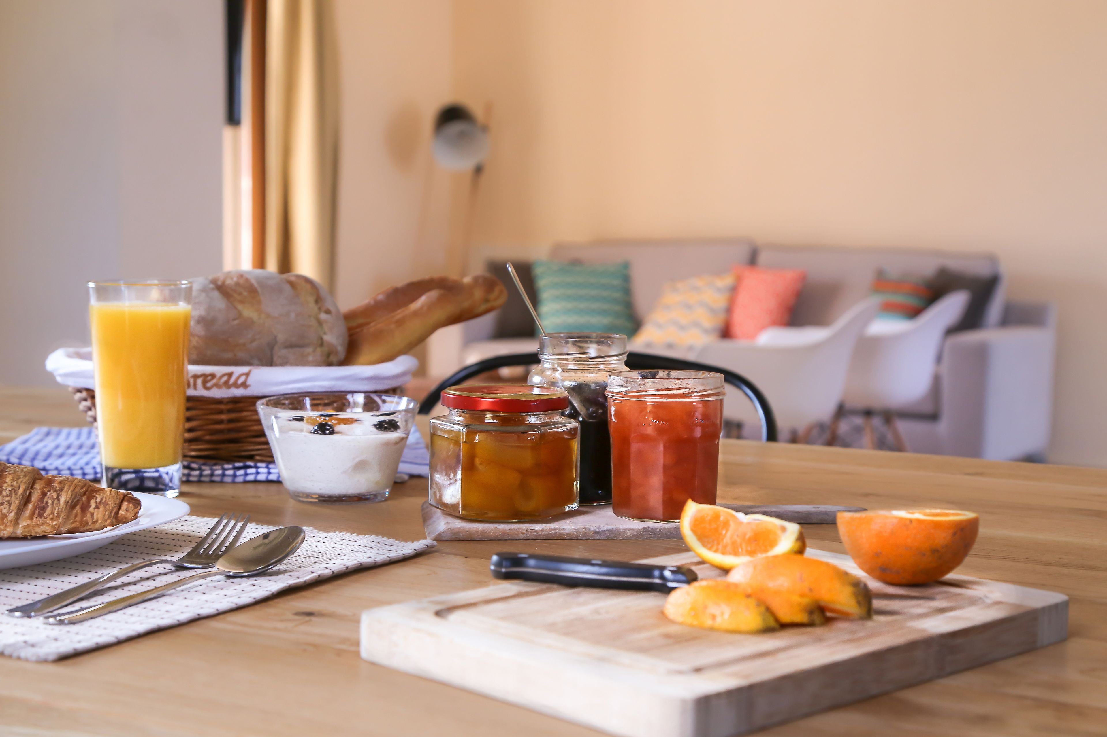 Een ontbijttafel met croissants, sinaasappelsap en verschillende soorten jam.