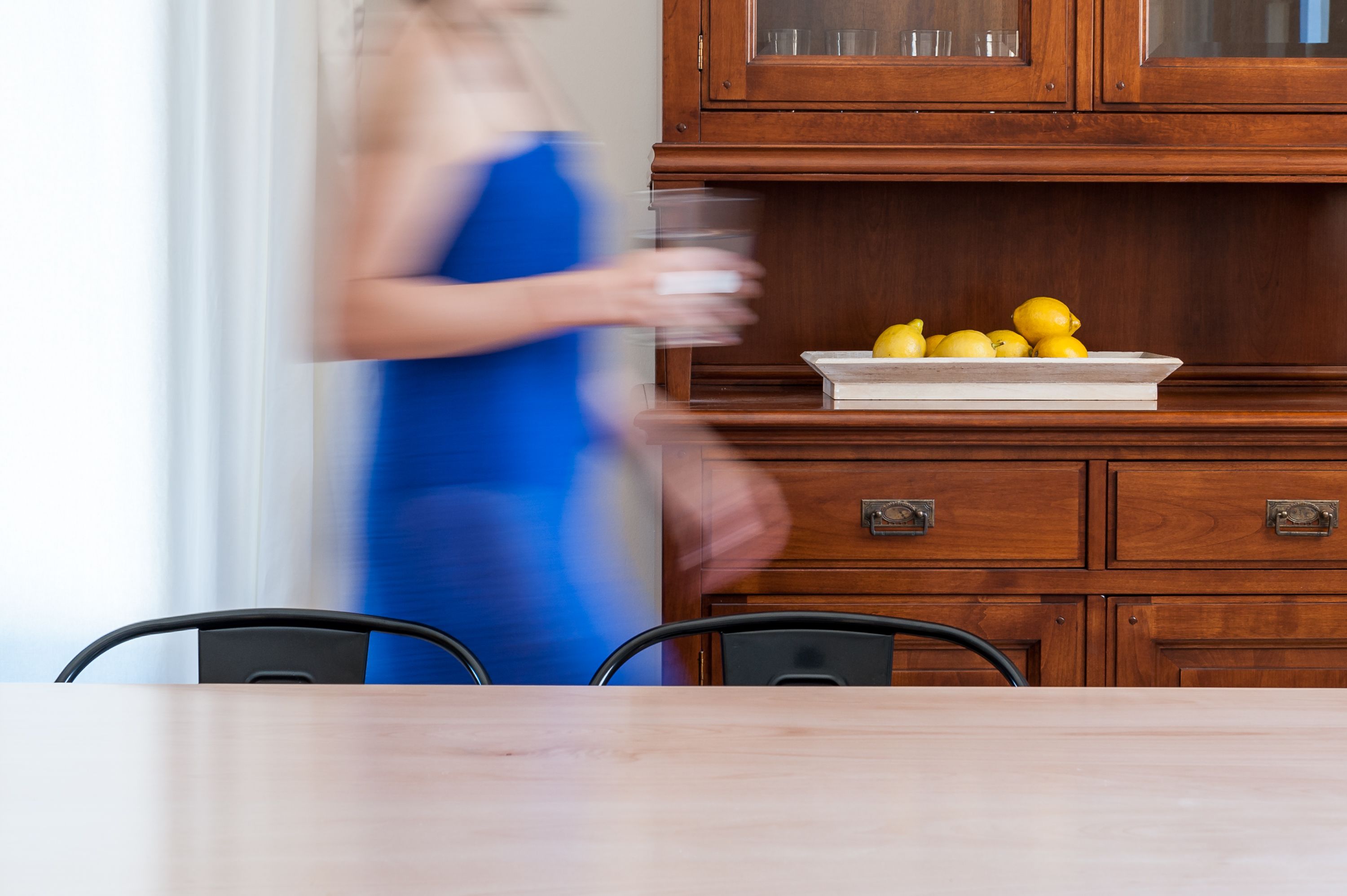Un comedor con mesa de madera, sillas y un armario con puertas de vidrio.