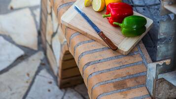 A brick barbecue grill with sausages and vegetables.