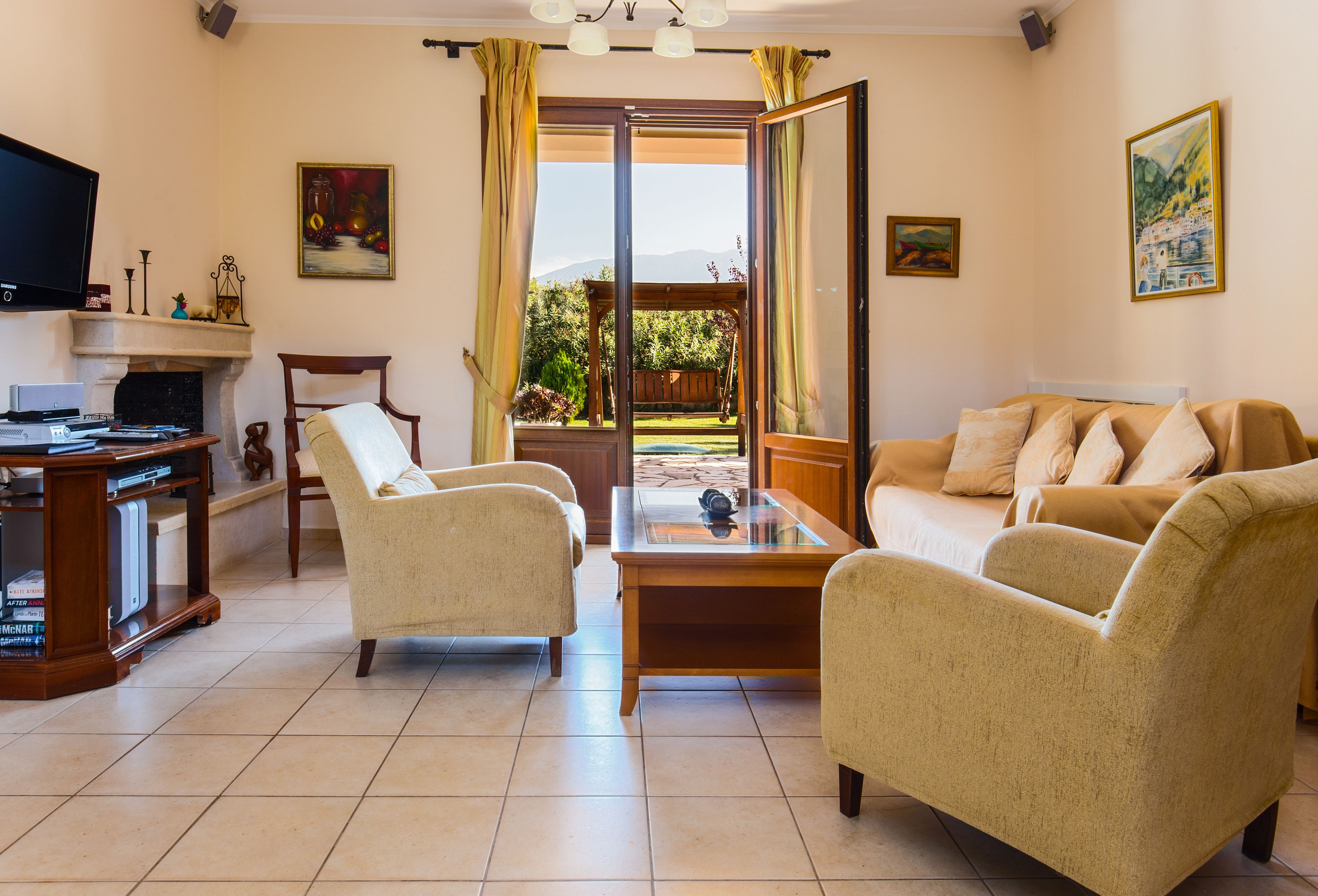 A living room with a sofa, armchairs, a coffee table, a fireplace, a television, and a view of the outdoors.