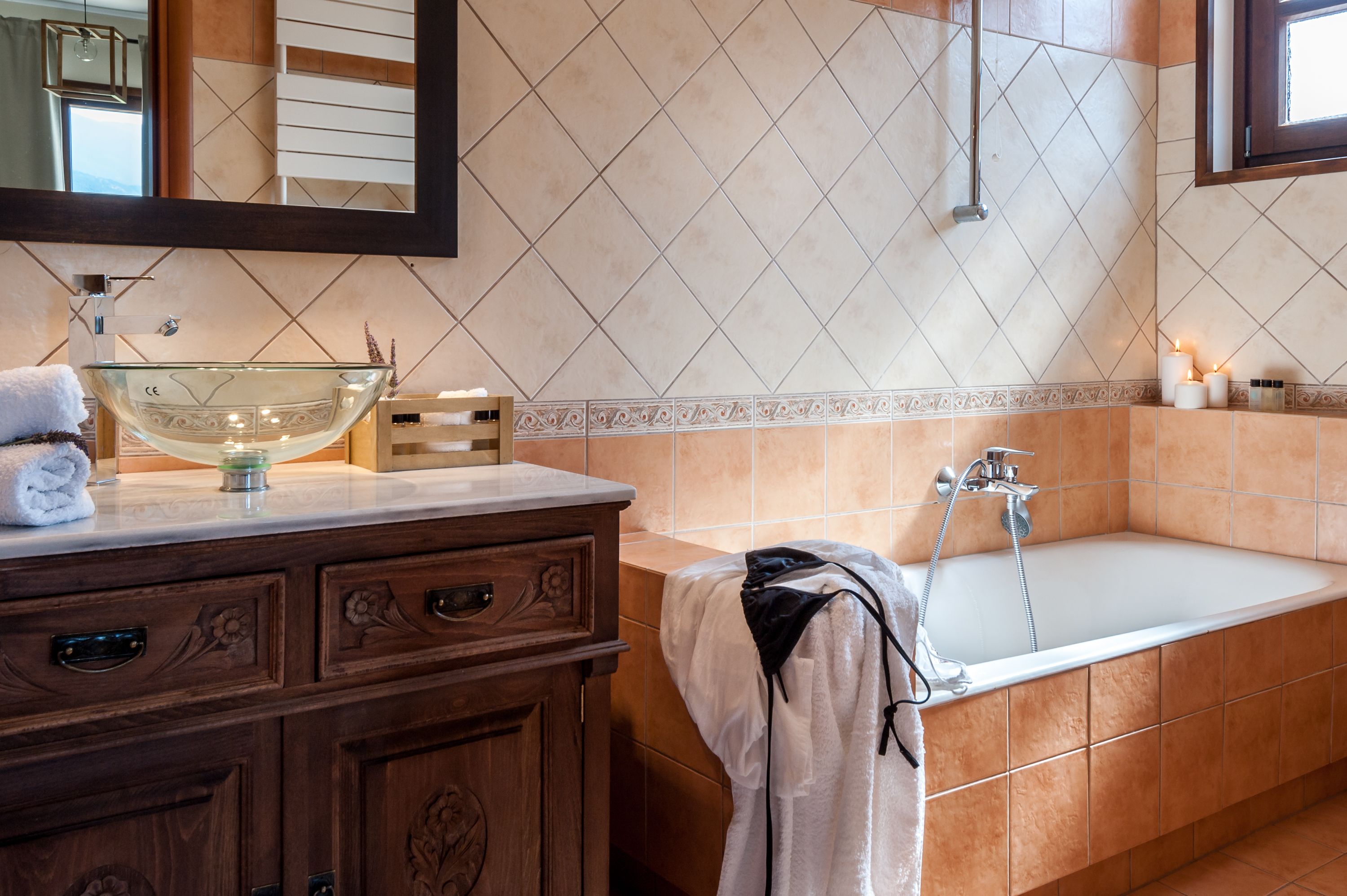 A bathroom with a glass bowl sink, wooden vanity, and a bathtub.