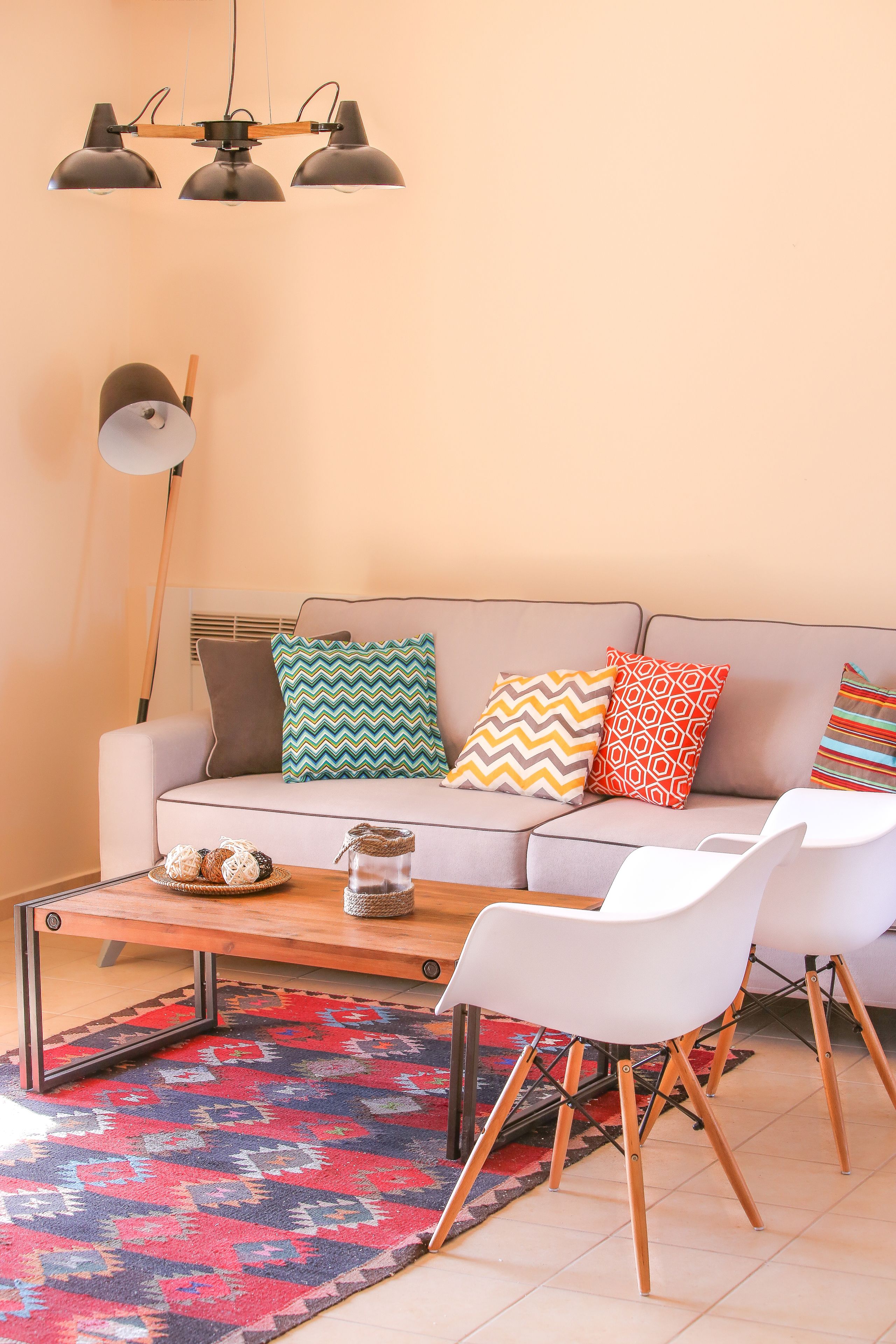 Ein Wohnzimmer mit einer Couch, gemusterten Kissen, einem Couchtisch und modernen Sesseln.