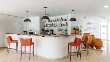 Un espace bar comprenant un comptoir, des tabourets de bar et un mur où sont exposées des bouteilles d’alcool.