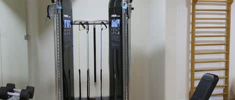 Un gimnasio con equipo de levantamiento de pesas, una banca y una barra para dominadas.