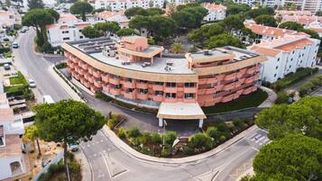 A multi-story hotel with a curved facade, multiple balconies, and a rooftop terrace.