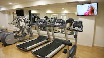 Un gimnasio con cintas de correr, elípticas y una pantalla de televisión.