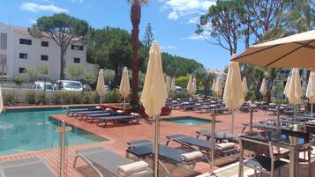 A poolside area with sun loungers, umbrellas, and a pool.