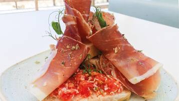 Un plato con jamón serrano y tomate sobre una rebanada de pan.