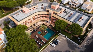 Luchtbeeld van een hotel met een zwembad, terras en parkeerplaats.