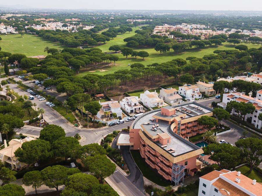 An aerial view of a residential area with houses, a golf course, and a swimming pool.