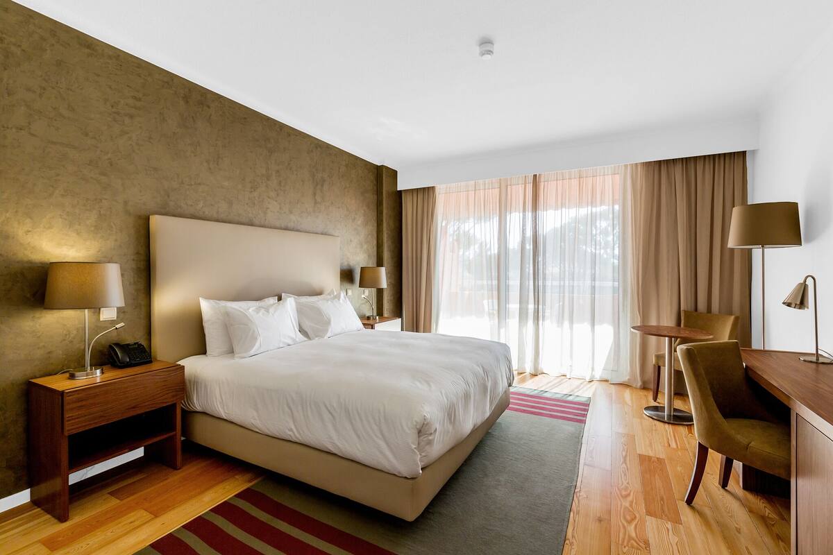 Una habitació d'hotel amb un llit gran, làmperes de sobretaula, un escriptori i una cadira.
