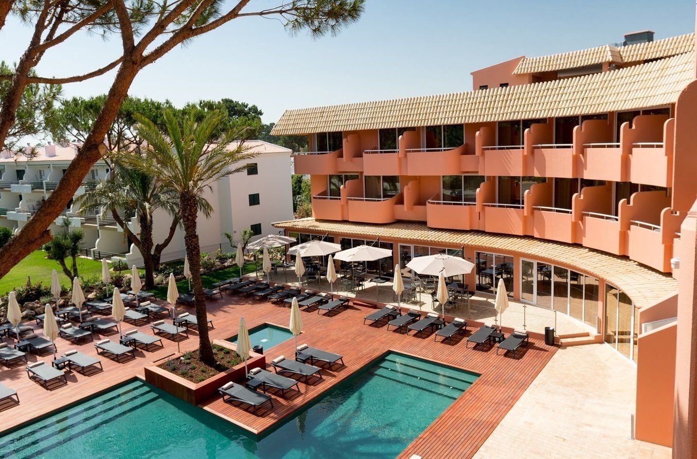 A hotel with a pool area, multiple balconies, and outdoor seating.
