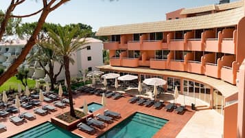 A hotel with a pool area, multiple balconies, and outdoor seating.