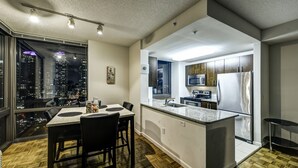Una cocina moderna con una isla grande, electrodomésticos de acero inoxidable y vistas a la ciudad a través del ventanal.
