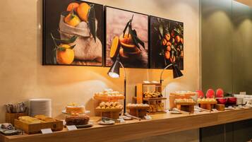 Una mesa de buffet con diversos alimentos y una presentación de frutas en la pared.