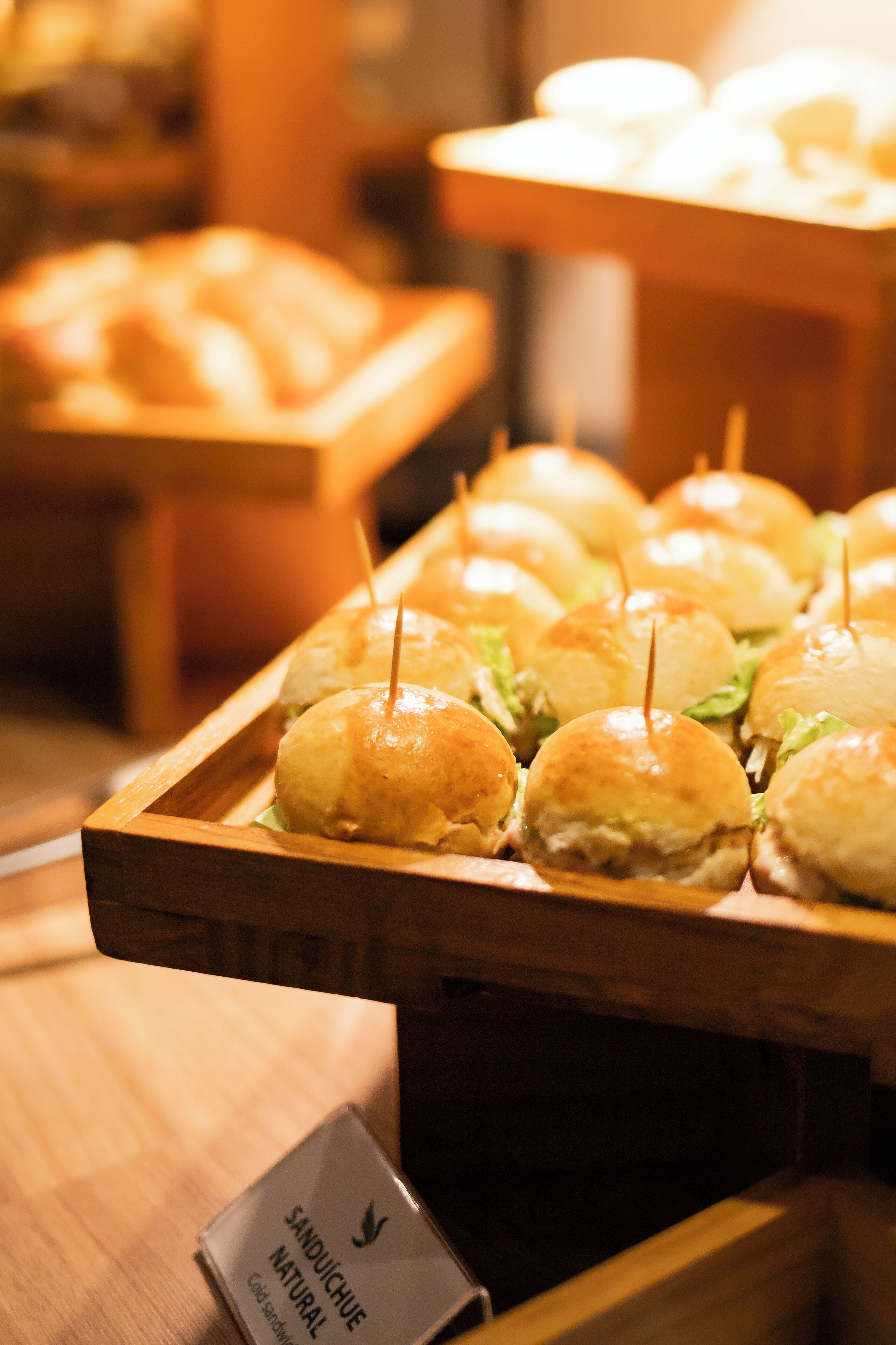 A tray of sandwiches with toothpicks, placed on a wooden table.