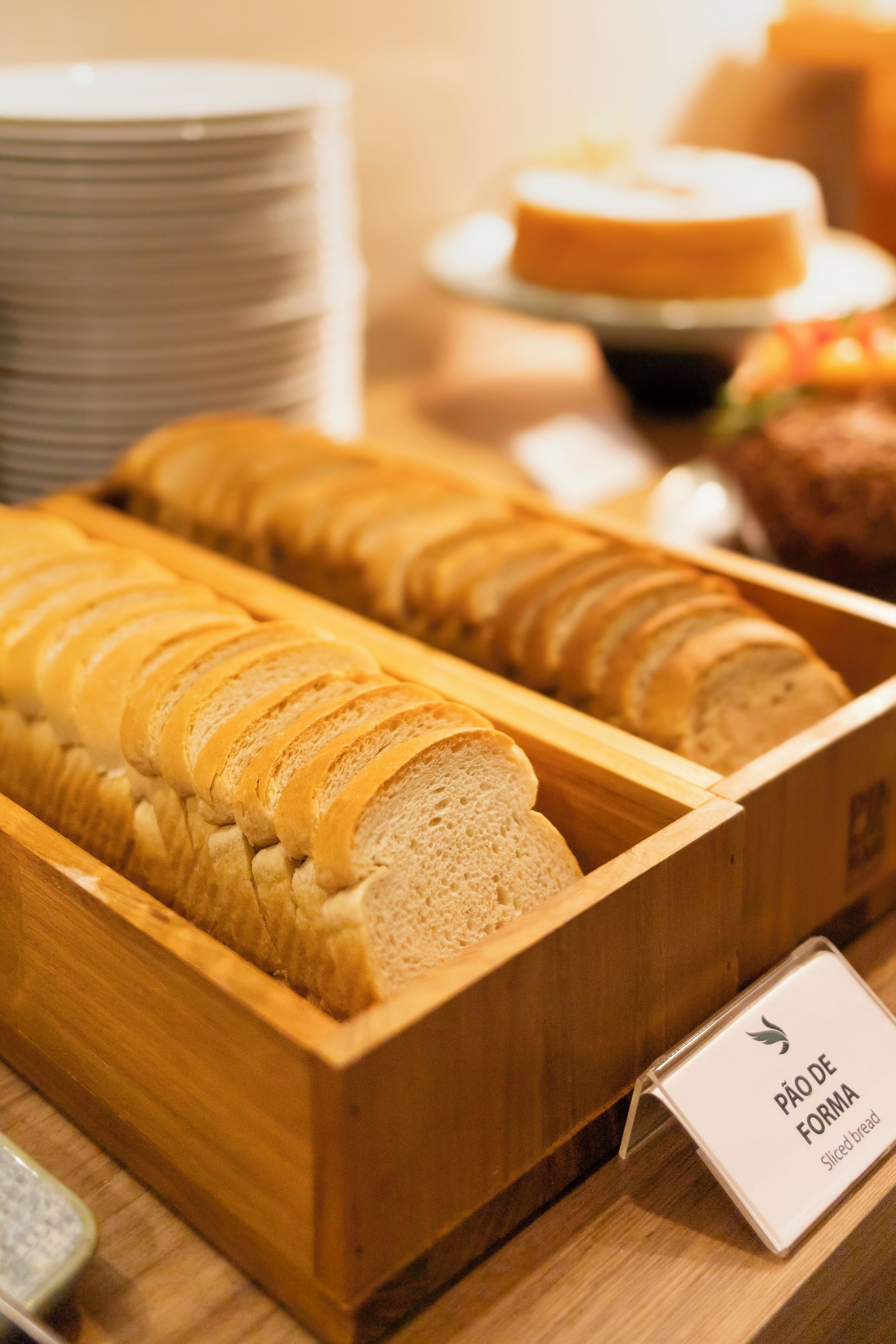 Un espositore di legno con pane a fette, con l'etichetta 'Pão de Forma Sliced bread'.