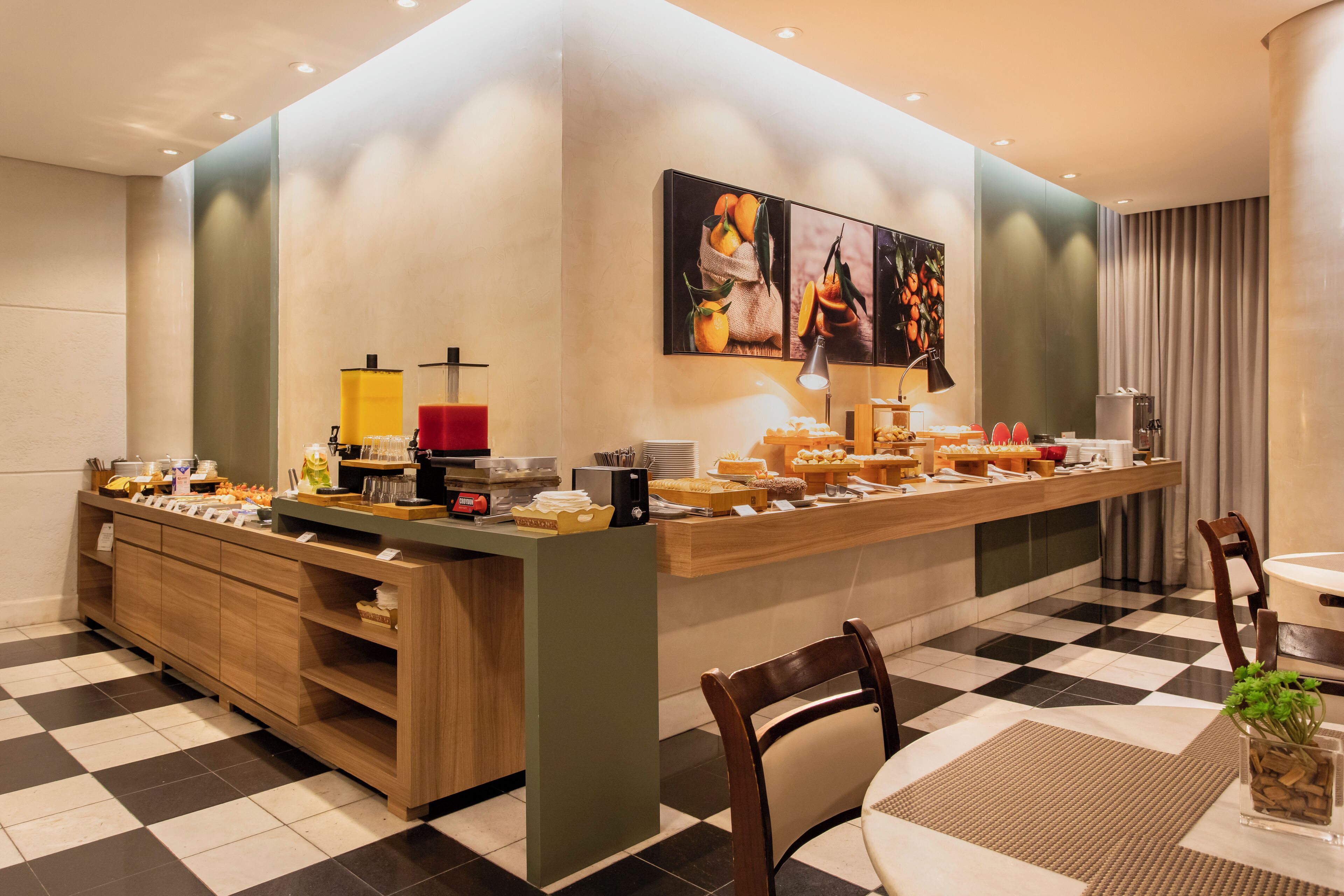 A breakfast bar with a variety of food items and a coffee machine. There is a wooden cabinet with shelves and a checkered floor.
