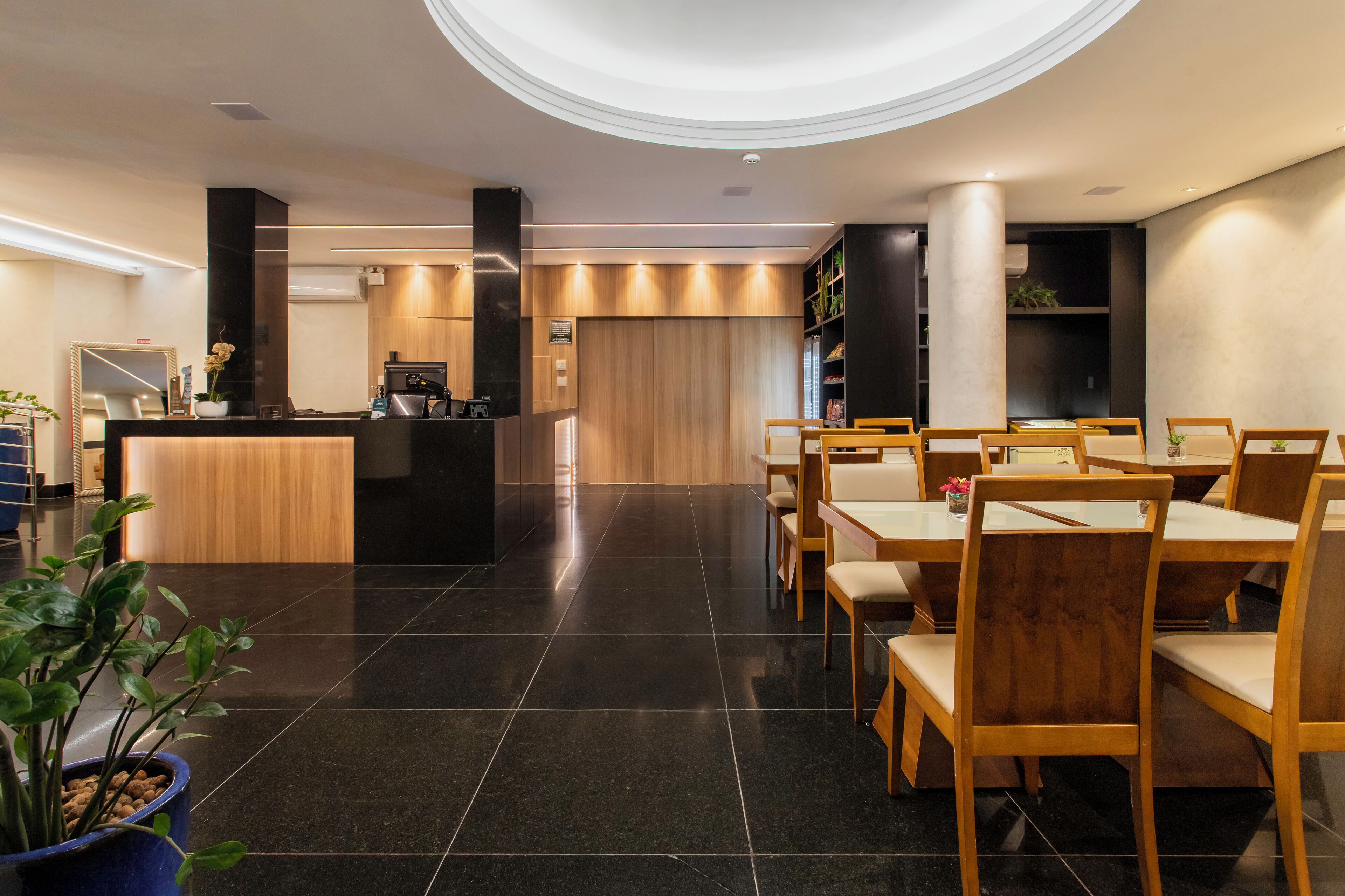 Un restaurante moderno con una barra central, sillas de madera y un suelo de baldosas negras.