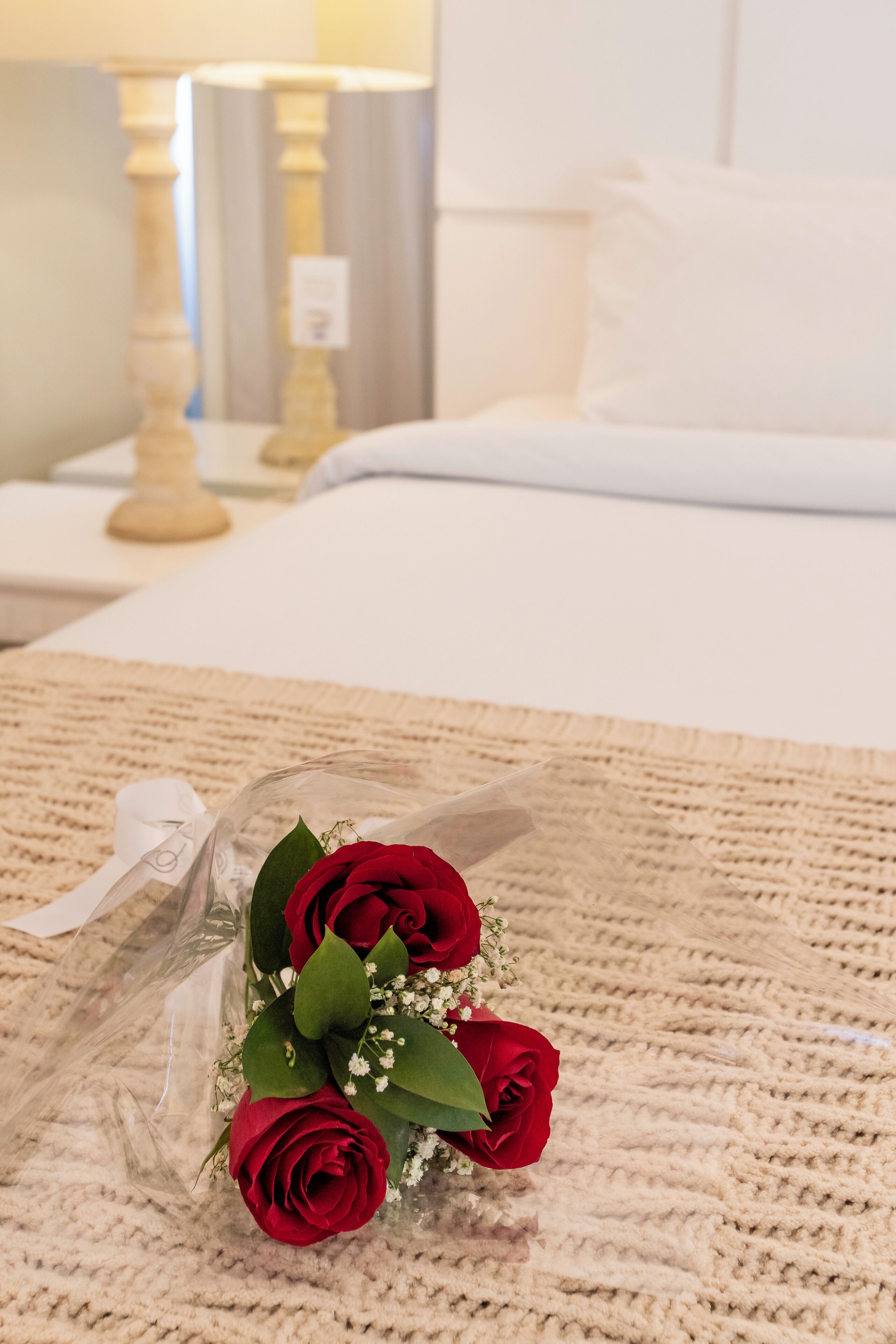 Un ramo de rosas rojas sobre una alfombra beige con textura.