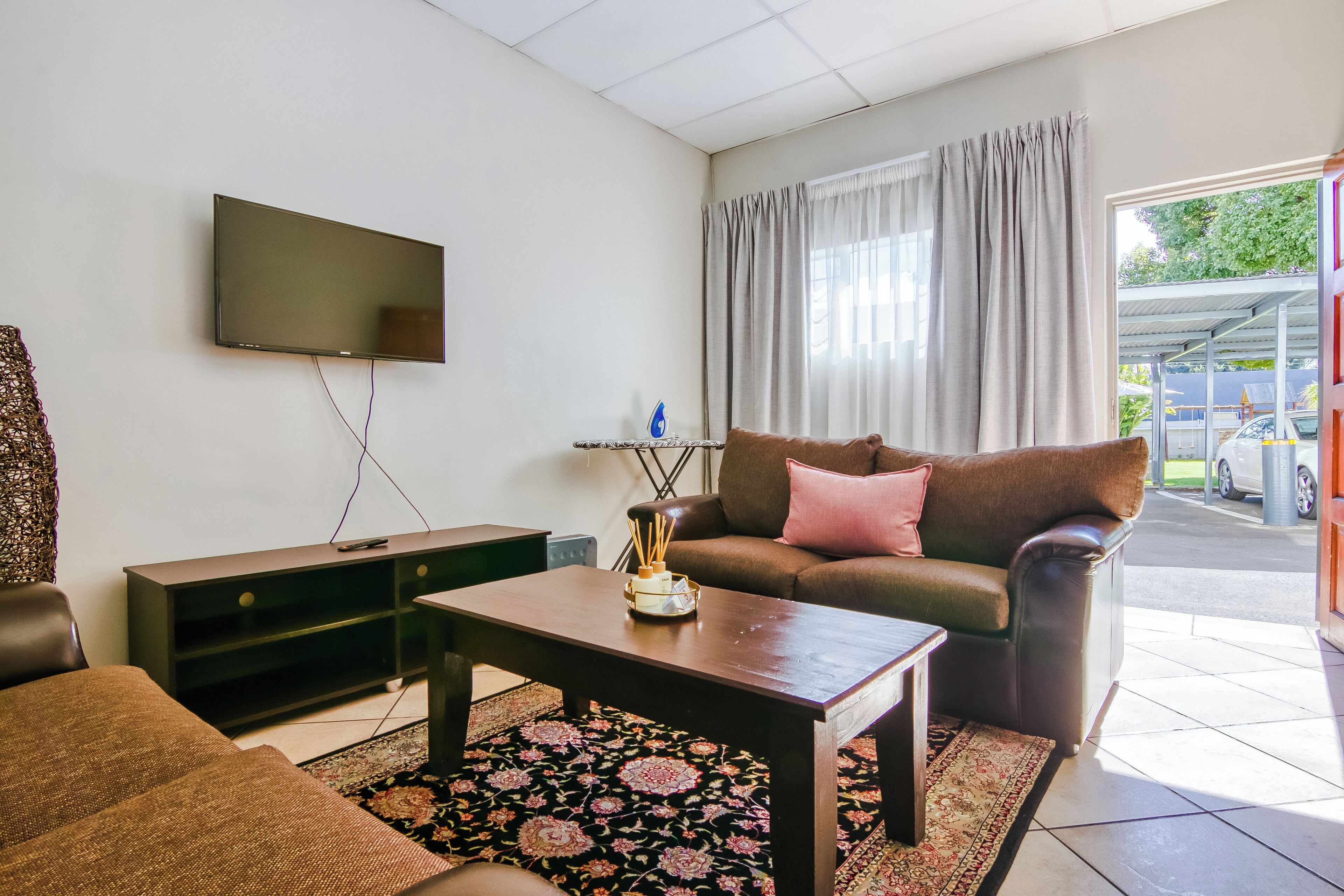 Un salon comprenant un canapé, une table basse, un téléviseur à écran plat, une petite table d’appoint et une fenêtre avec des rideaux.