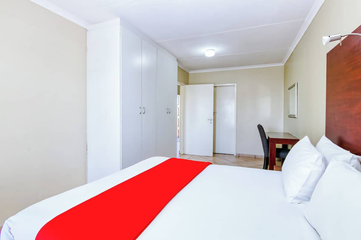 A hotel room with a bed, a desk, and a wardrobe.