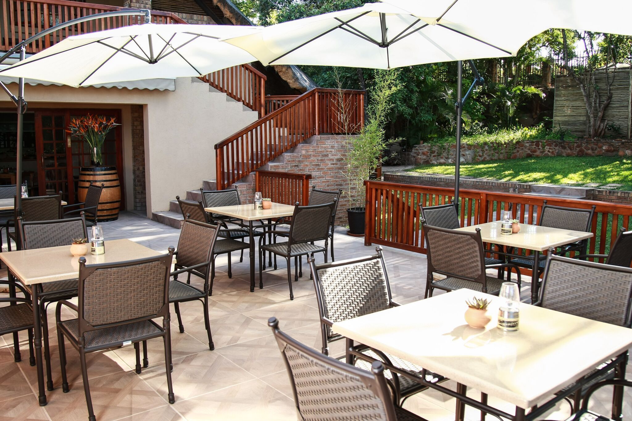An outdoor patio area with multiple tables and chairs, surrounded by a wooden deck and a brick staircase.