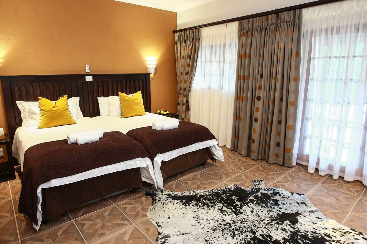 Una camera d'albergo con due letti, un tappeto grande e tende.