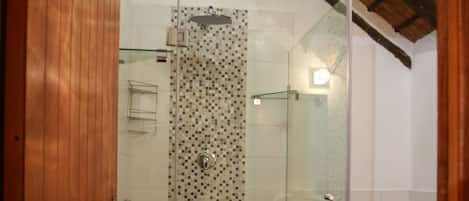 A bathroom with a glass-enclosed shower, a toilet, and a tiled floor.