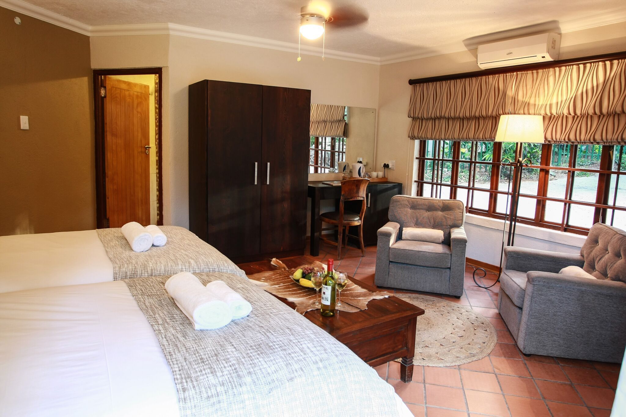 Une chambre d’hôtel avec deux lits, un bureau, une chaise et un canapé.