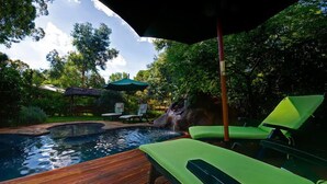 A wooden deck with a hot tub, green lounge chairs, and a waterfall feature. - Woodland Gardens (Magaliesberg)