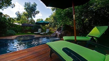 Relax by the pool surrounded by lush greenery and a soothing waterfall.
