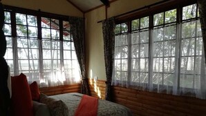A room with a bed, a lamp, and large windows with curtains. - Woodland Gardens (Magaliesberg)