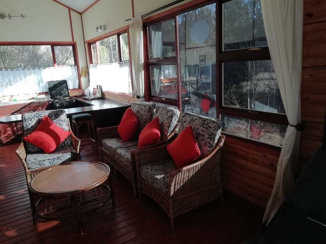 Une pièce chaleureuse, meublée de meubles en osier, avec une petite table et de grandes fenêtres donnant sur l’extérieur.