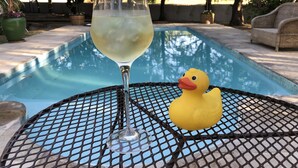 A glass of white wine on a table by a pool with a rubber duck. - Wittedrift Manor House (Tulbagh)