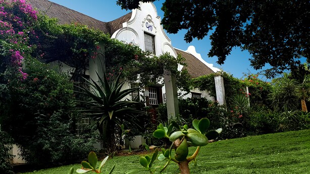 A building with a white facade, green roof, and a large window. - Wittedrift Manor House (Tulbagh)
