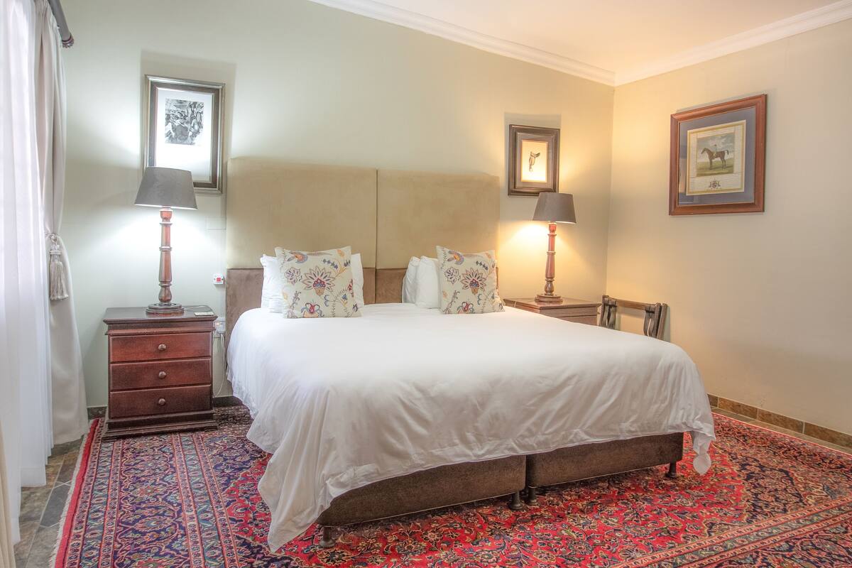 A neatly arranged bedroom with a bed, two bedside tables, a lamp, and a patterned rug.