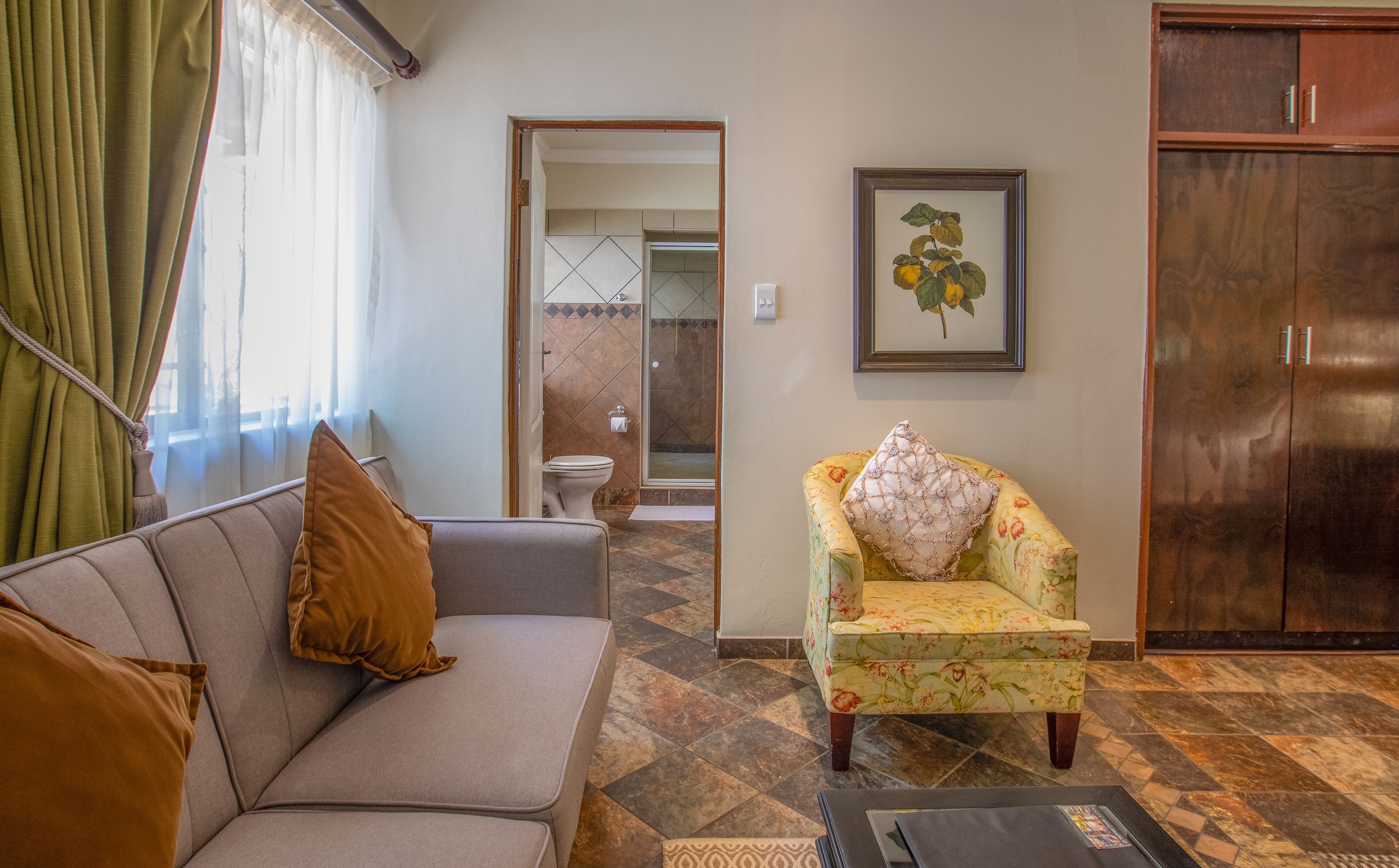 A living room with a sofa, armchair, and a framed picture on the wall.