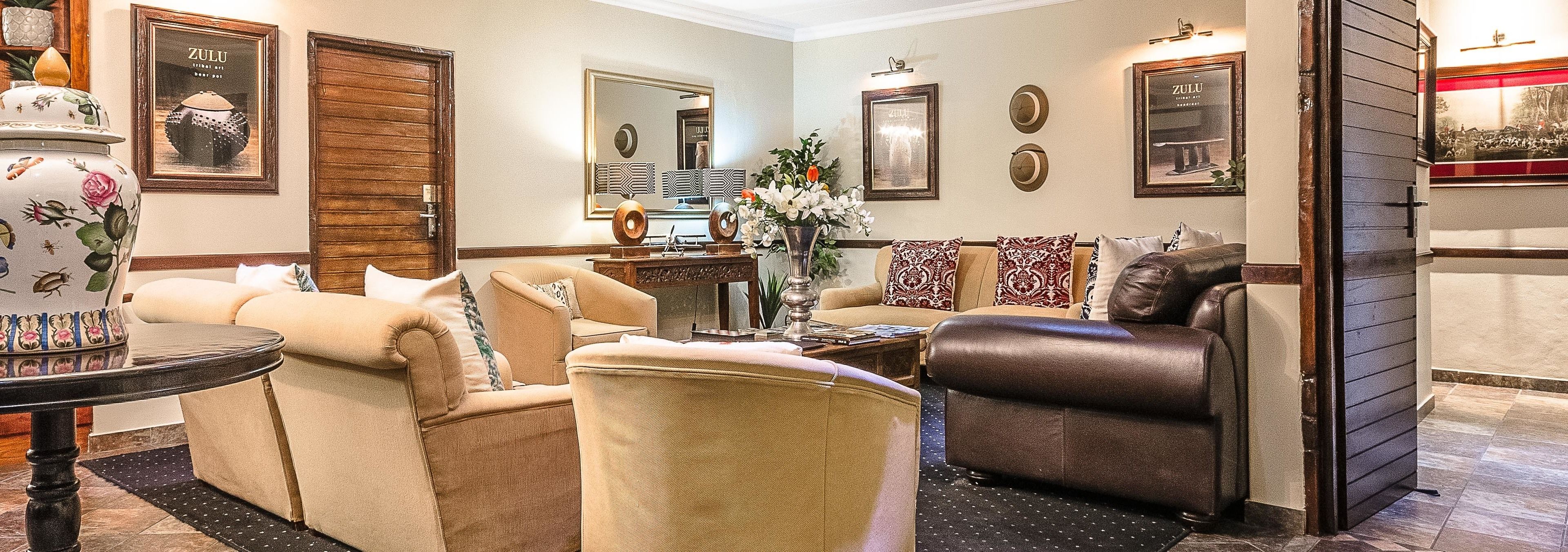 Una sala de estar bien amoblada, con un conjunto de sofá color beige, un sillón de cuero marrón, una mesa de centro y un jarrón decorativo con flores.